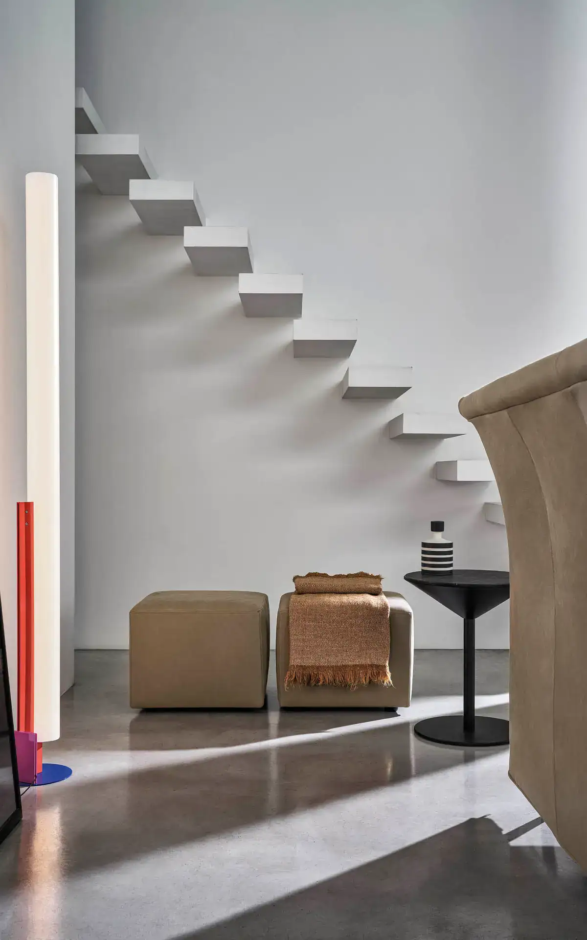 Luce da soggiorno moderna con sedute e scala sospesa in stile minimalista.