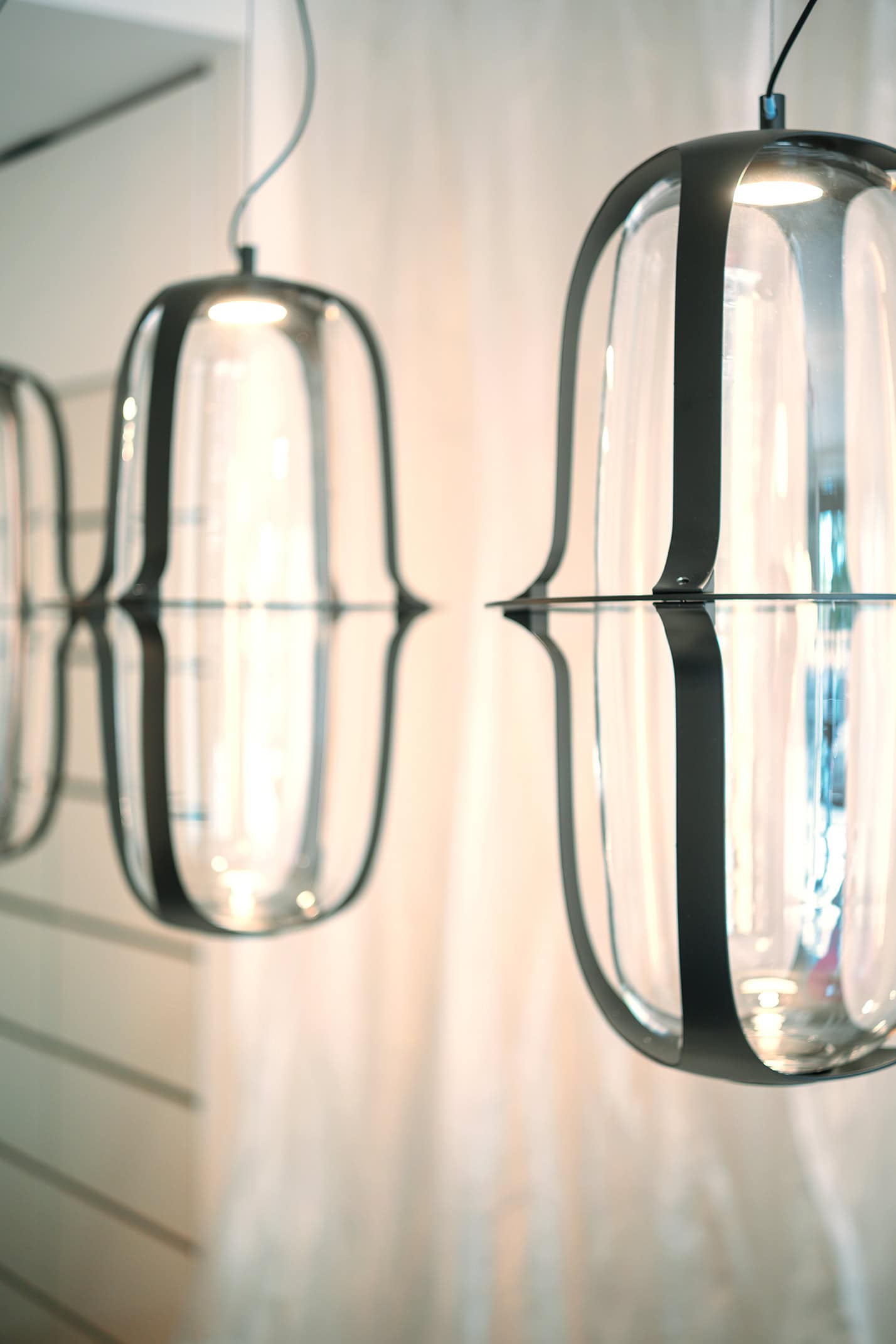 Lampi pendenti moderni in vetro e metallo, design minimalista, esposizione Milano 2023.