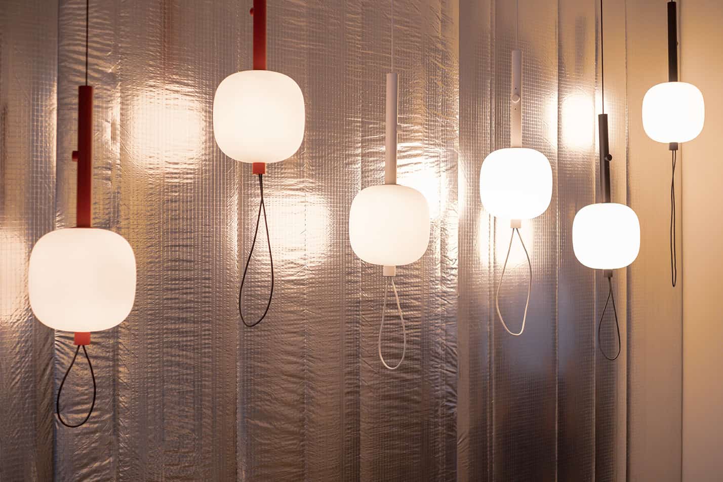 Luci pendenti in vetro bianco con dettagli colorati, design moderno e materiali leggeri.